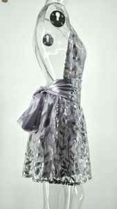 Détail d'une robe de soirée à paillettes argentées avec un nœud en satin et dos nu