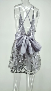 Détail d'une robe de soirée pailletée argent avec dos nu croisé et grand nœud satin