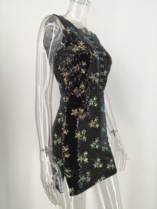 Detail of slim-fit black sequined dress with blue and gold floral patterns and side slit