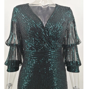 Close-up of emerald green sequins on double-layered ruffled sleeves of a V-neck dress