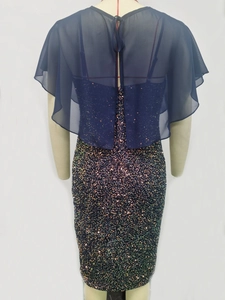 Detail view of the back of a sequined cocktail dress with a sheer chiffon capelet overlay