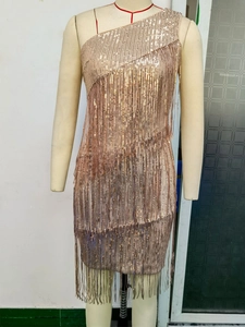 Close-up of champagne gold sequined dress featuring long fringe and one-shoulder cut