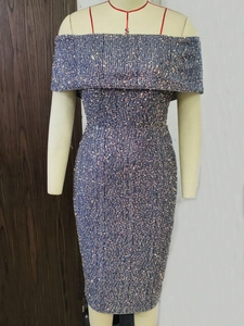 Close-up of sparkling green sequins and off-shoulder design on a slim-fit cocktail dress