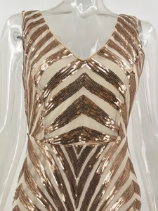 Close-up of gold sequins and geometric stripe patterns on a backless evening party gown