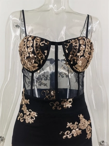 Detail of sequin floral patterns and sheer mesh corset on a black gold evening gown