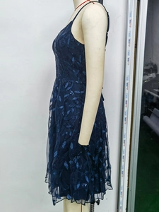 Detail of navy blue prom dress showing intricate leaf embroidery and shimmering sequins