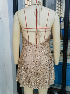 Detail of the backless sequin dress showing champagne gold sparkle and crisscross straps