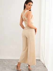 Detail of beige wide-leg jumpsuit with open back cross straps and pleated fabric texture