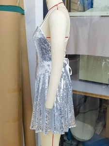 Detail of silver sequined mini dress featuring open back with white criss-cross ties