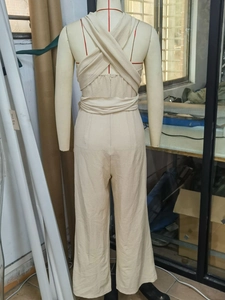 Detailed view of backless halter jumpsuit featuring crossover straps and textured crepe fabric
