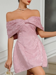 Detail of pink off-shoulder prom dress featuring floral jacquard fabric and bow design