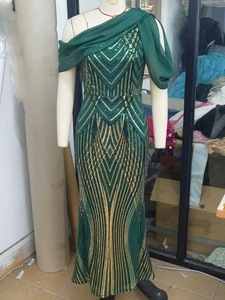 Detail of green evening dress with golden geometric sequins and a chiffon shoulder drape