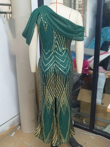 Detail view of emerald green sequined evening dress with one-shoulder chiffon shawl detail