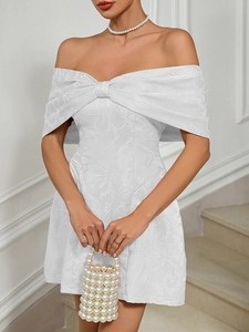 Close-up of white strapless party dress featuring a large bow and jacquard fabric texture