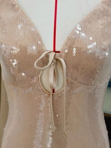 Detail of champagne sequin evening dress featuring hollowed-out ring and lace-up design
