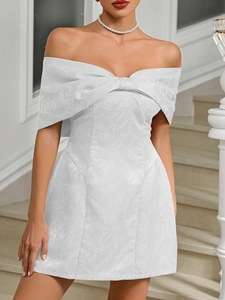 Detail of white off-shoulder mini dress featuring textured jacquard fabric and bow