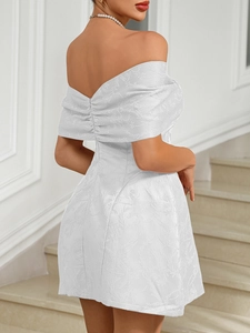 Macro view of white off-shoulder mini dress with elegant floral jacquard fabric texture