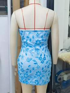 Détail d'une mini robe bleu clair avec broderie florale et paillettes sur tissu ajusté