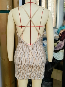 Detail of sequined bodycon mini dress showing gold and silver wavy patterns and back straps