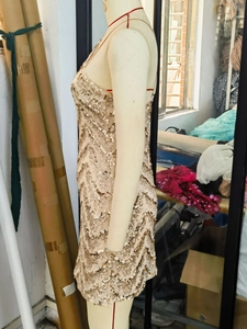 Détail de la robe de soirée à paillettes dorées avec motif ondulé sur mannequin