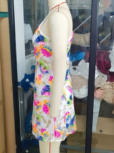 Detailed view of colorful floral sequin embroidery on white sleeveless mini dress