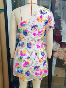 Detail of one-shoulder sequin dress with colorful floral patterns and sheer mesh