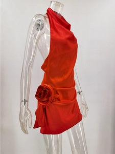 Detail of red satin halter dress featuring a large 3D rose and backless party design