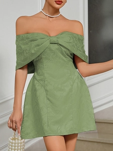 Detail of green off-shoulder dress featuring floral jacquard fabric and a large bow