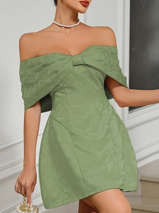 Detail of lime green mini dress featuring textured floral fabric and a large bow design