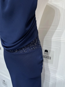Détails d'une robe en mousseline bleu foncé avec taille pailletée et texture de tissu verticale