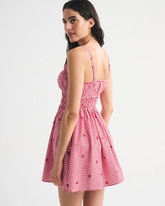 Close-up of red gingham floral summer dress with strawberry embroidery and smocked bodice