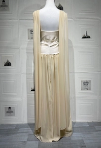 Dettaglio dell'abito lungo in chiffon champagne con mantella elegante e vita plissettata