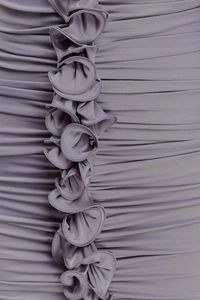 Detailed view of purple ruched fabric with vertical ruffles and fine knitted texture