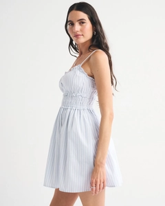 Detail of light blue striped summer dress featuring spaghetti straps and smocked waist