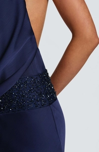 Gros plan des paillettes faites main et de la texture ondulée sur la robe bleu marine