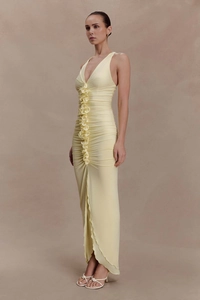Close-up of elegant pale yellow sleeveless dress featuring ruffles and asymmetric slit