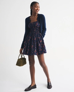 Detail view of navy blue cardigan and strawberry print dress with green handbag