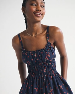 Detailed view of the strawberry print fabric and smocked waist on a navy summer dress