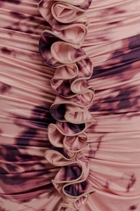 Macro view of pink tie-dye fabric with subtle gloss, ruching details, and ruffled edges