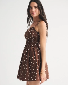 Detailed side view of a brown polka dot camisole dress with pleated bust and slim fit waist