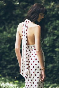 Detail of a white halter neck dress with red polka dots and an elegant open back design