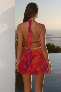 Dettaglio del top a schiena scoperta e gonna a balze con stampa tie-dye rossa e viola
