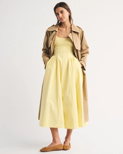 Detail of slim yellow dress paired with a classic khaki trench coat and ballet flats