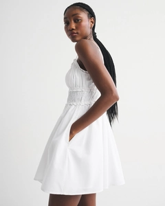 Detail view of white mini dress featuring smocked bodice and delicate spaghetti straps