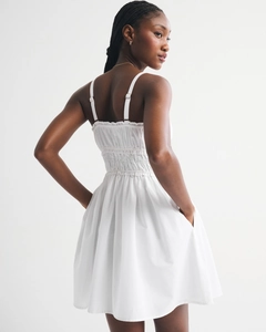 Detail of white floral sundress showing smocked back with adjustable straps and pockets