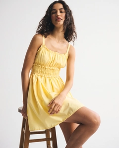 Detail of yellow smocked sundress with thin straps and floral pattern for summer