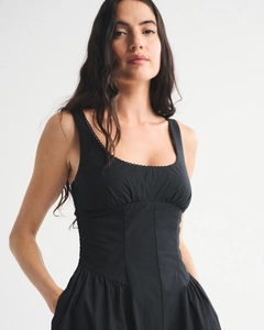 Detail of square neckline with delicate lace trim on a slim fit black sleeveless dress