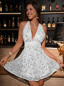 Close-up of white halter dress featuring silver sequin leaf patterns and deep V-neckline