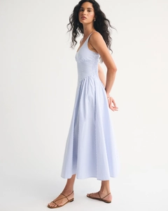 Detail of light blue striped midi dress with pleated skirt and breathable cotton texture