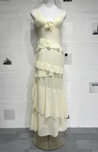 Detail view of cream backless slip dress featuring a 3D rose and layered ruffle hem
